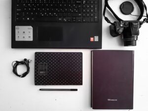 black and red laptop computer beside black headphones and black headphones